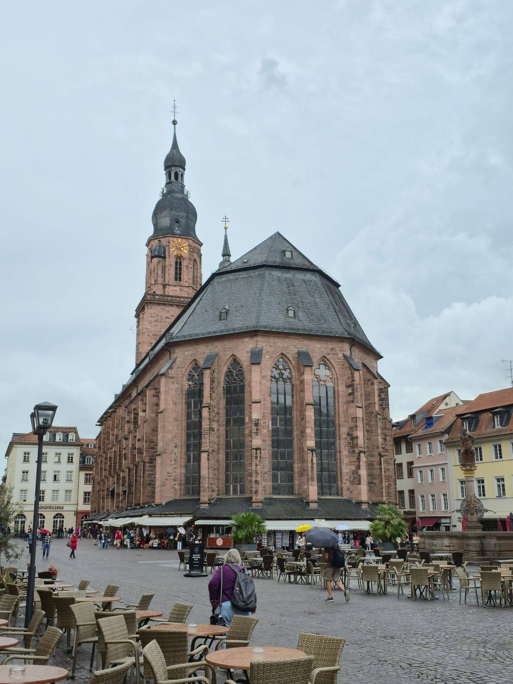 Die Heiliggeistkirche am Marktplatz, davor Tische und Schirme der Cafés