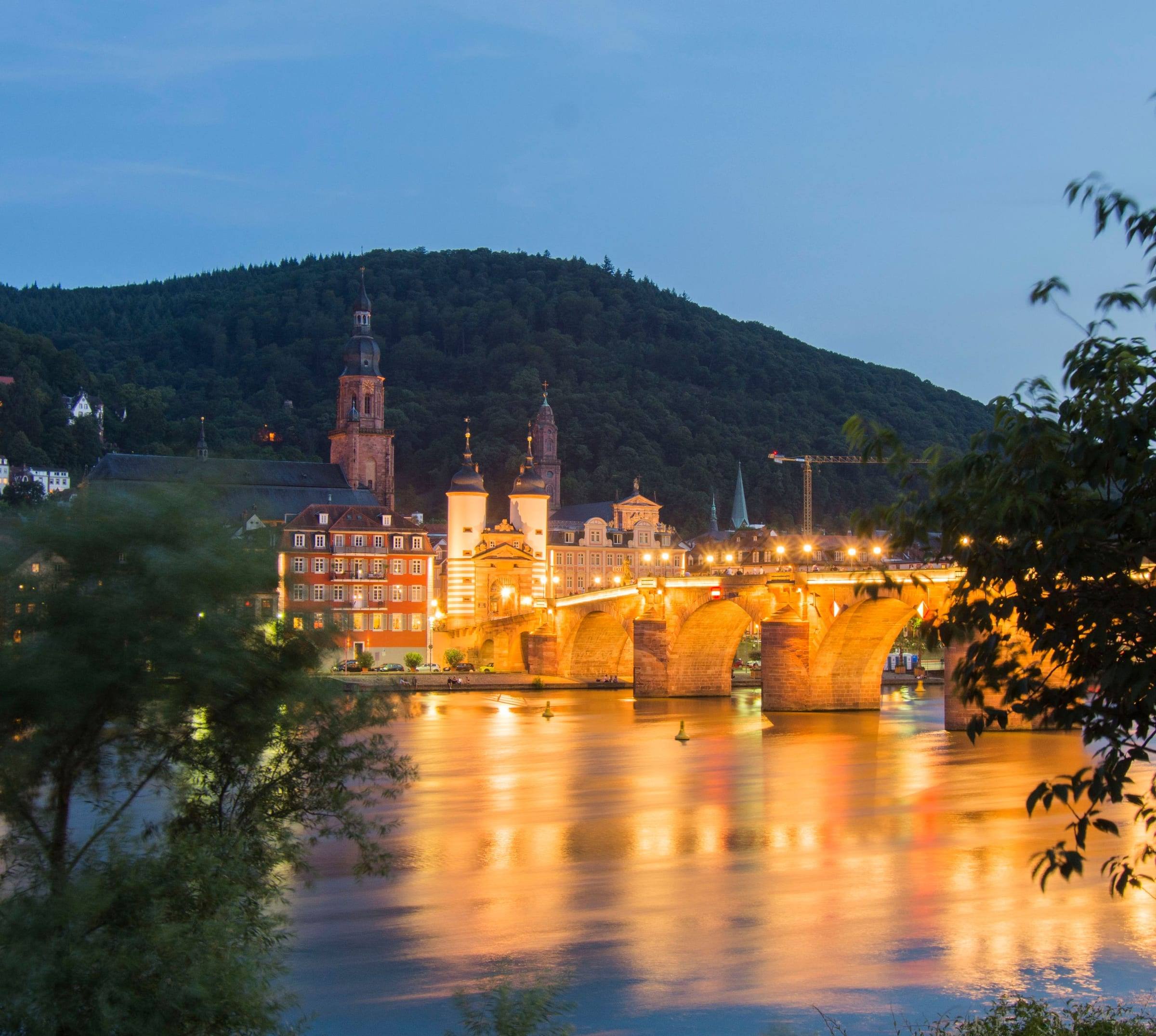 Beleuchtete Alte Brücke und Brückentor in der Dämmerung, im Neckar gespiegelt
